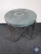 An antique Eastern copper topped table on a folding oak base