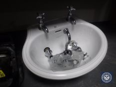 A Heritage hand basin with taps together with a set of bath taps and a mixer tap