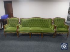 A carved three piece lounge suite in green buttoned fabric