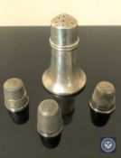 A silver pepperette and three silver thimbles