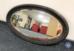 A heavily carved mahogany oval mirror