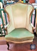 A continental carved wingback armchair in green upholstery
