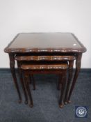 A mahogany nest of three glass topped tables