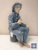 A Nao figure of a fisherman seated smoking a pipe, in matt finish,