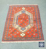 A Caucasian design rug on red ground,