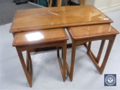A nest of three glass topped teak tables