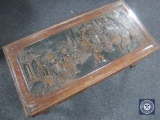 A heavily carved oriental glass top coffee table