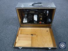 A cased Singer electric sewing machine with foot pedal