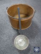 A large copper cooking pot with ladle