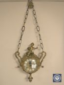 A continental gilt metal suspension clock with enamel dial and surmounted with a cherub,