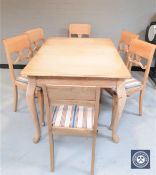 A blond oak dining table on cabriole legs and matching set of six dining chairs in striped