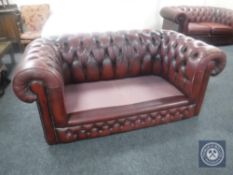 A red buttoned leather two seater Chesterfield settee,
