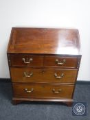 An antique mahogany writing bureau fitted four drawers with brass drop handles on bracket feet