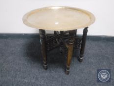 An Eastern brass topped table on folding base