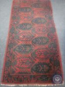 An Afghan design rug on red ground, 198cm by 100cm,