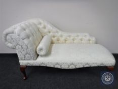 A contemporary chaise longue upholstered in a cream buttoned floral print