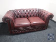 A red buttoned leather two seater Chesterfield settee