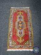 A fringed Eastern hearth rug on claret ground,