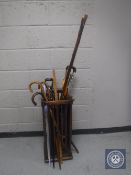 An Edwardian oak Arts & Crafts stick stand containing a quantity of walking sticks,