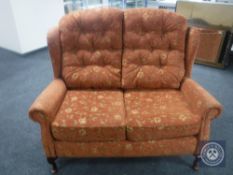 A wingback two seater settee upholstered in a red floral fabric