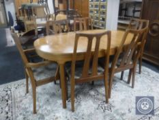 An oval teak Nathan extending dining table with six chairs