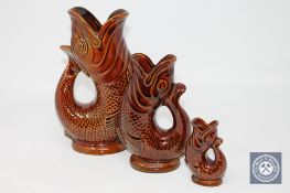 A graduated set of three Dartmouth treacle glaze fish jugs