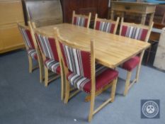 A pine refectory kitchen table together with a set of six blond oak dining chairs upholstered in a