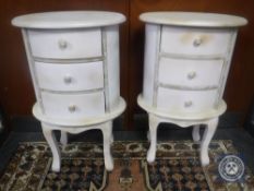 A pair of painted oval three drawer bedside chests