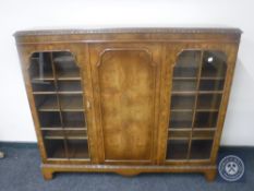 An early 20th century walnut triple door display cabinet on bracket feet