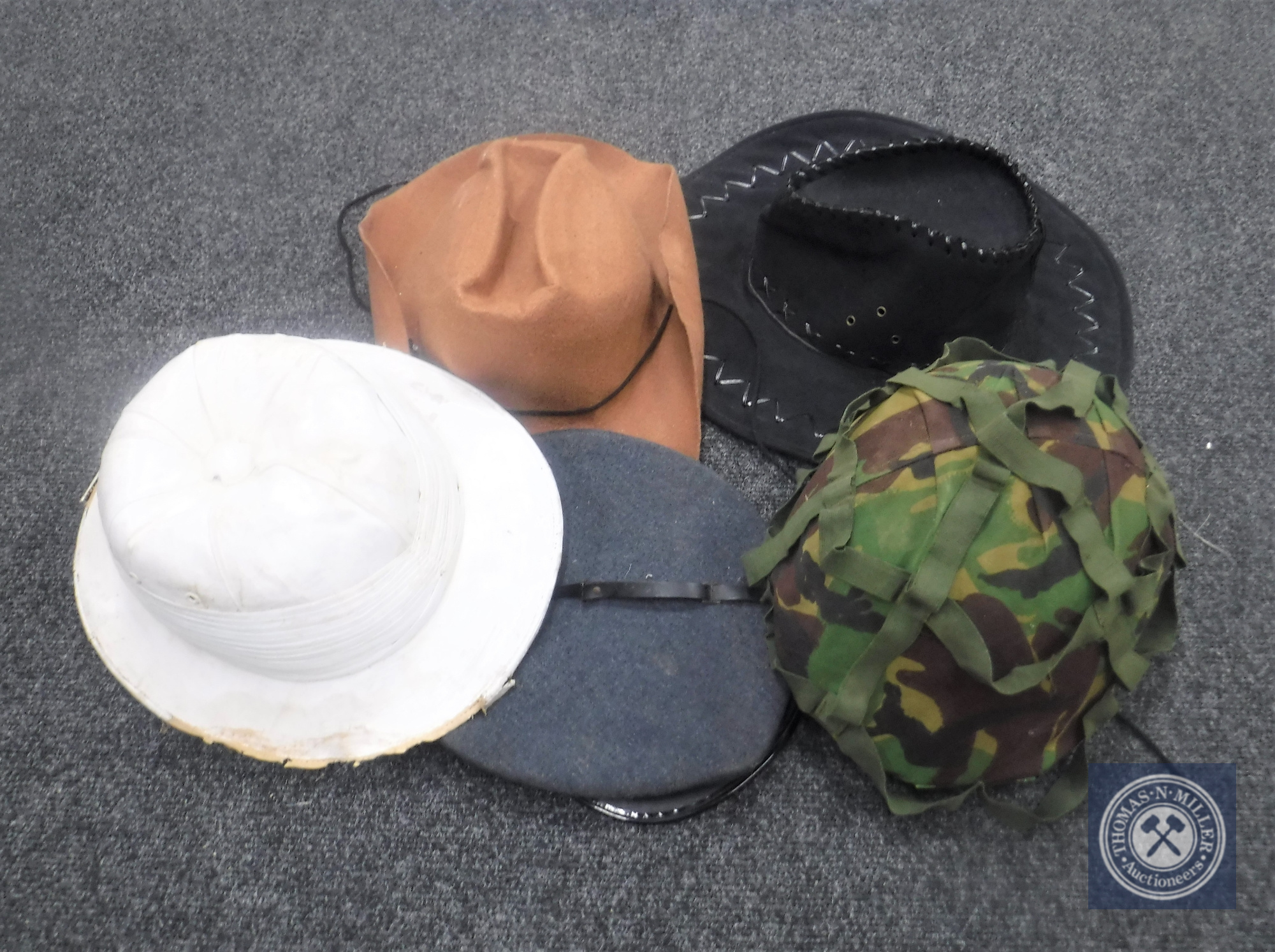 An army issue helmet together with a military cap,