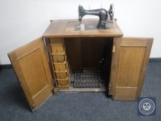 A mid 20th century Griznzer treadle sewing machine in a walnut cabinet