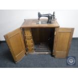 A mid 20th century Griznzer treadle sewing machine in a walnut cabinet