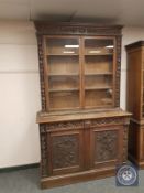 A Victorian heavily carved oak glazed bookcase fitted with cabinet base,