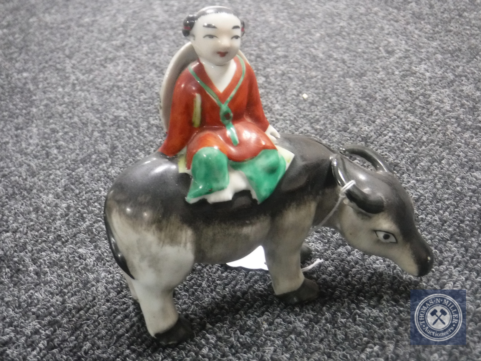 An early 20th century Chinese pottery figure of a man seated on a water buffalo, height 13.5 cm.