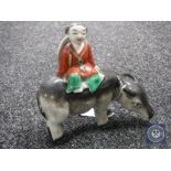 An early 20th century Chinese pottery figure of a man seated on a water buffalo, height 13.5 cm.