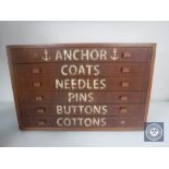 A mid 20th century teak six drawer counter topped chest containing buttons and sewing items