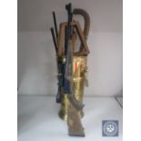 A brass lion mask handled stick stand containing sporting rackets and hockey sticks together with