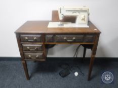 A Singer electric sewing machine in oak table and a table of sewing accessories