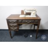 A Singer electric sewing machine in oak table and a table of sewing accessories