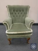 A id 20th century armchair upholstered in a green buttoned dralon