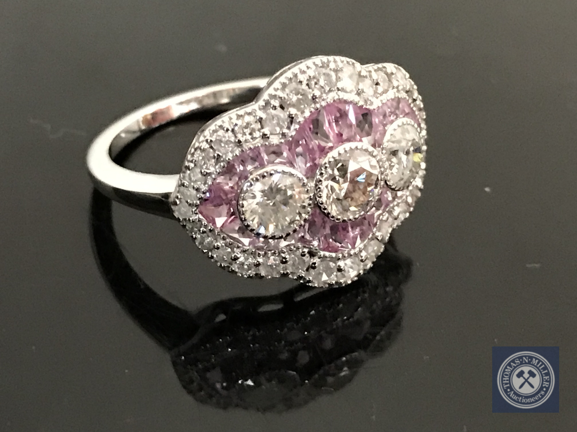 An 18ct white gold sapphire and diamond ring featuring 3 centre round brilliant cut diamonds,