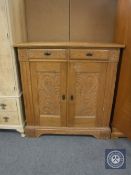 An early 20th century continental oak double door cabinet fitted two drawers with carved panel