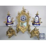 A three piece continental gilt and ceramic clock garniture with enamelled dial and pendulum