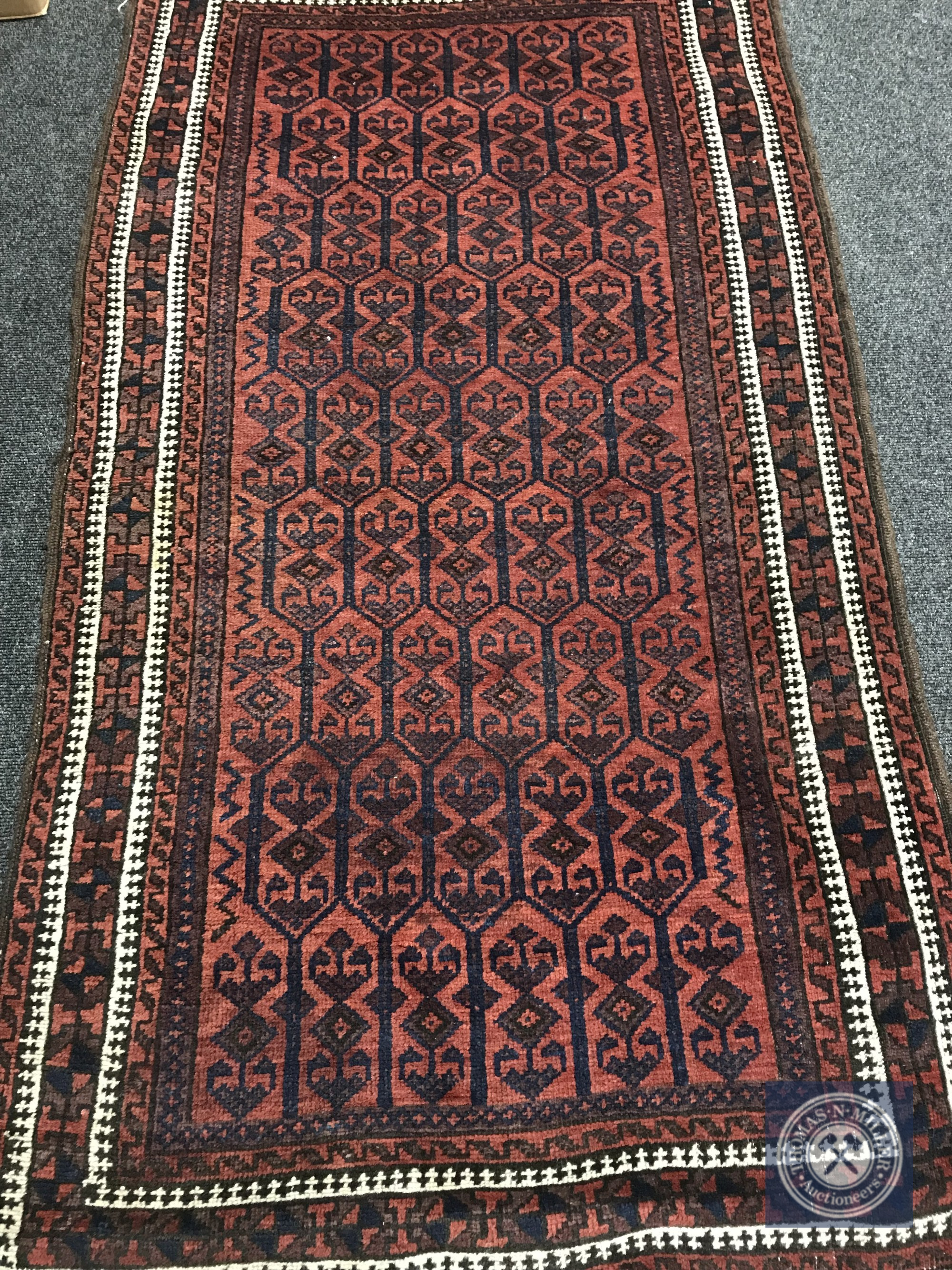 An Afghan rug on terracotta ground,