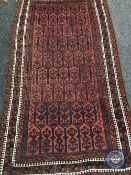 An Afghan rug on terracotta ground,