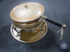 An antique hand hammered copper lidded pot on stand with burner,