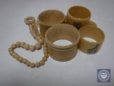 Five antique ivory napkin rings together with a beaded necklace