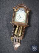 An oak sun and moon phase wall clock with pendulum and weights