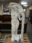 A contemporary carved solid white marble statue of a standing nude female pouring water from a