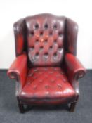 A red buttoned leather Chesterfield style wingback armchair